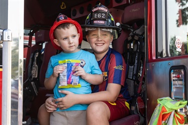 Two children wearing fire hats sit inside a Des Plaines fire truck.