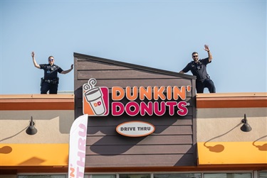 Two Des Plaines police officers stand on the roof of a Dunkin’ during a Cop on a Rooftop event.