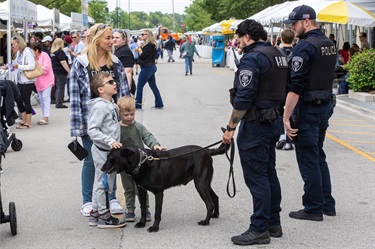Several young boys and an adult speak with a Des Plaines police canine officer during the Taste of Des Plaines festival.