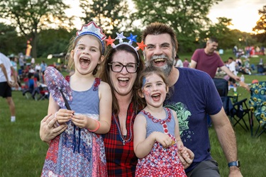 A family dressed in patriotic colors smiling while waiting for fireworks.