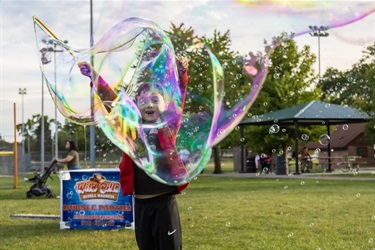 Child making a large bubble with a bubble wand at the Food Truck Round Up.