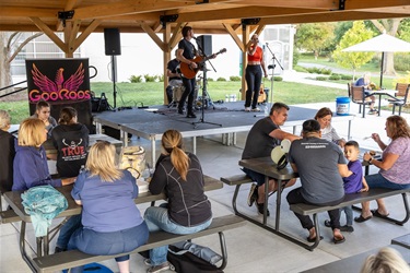 Visitors dining at picnic tables while a live band performs at the Food Truck Round Up.
